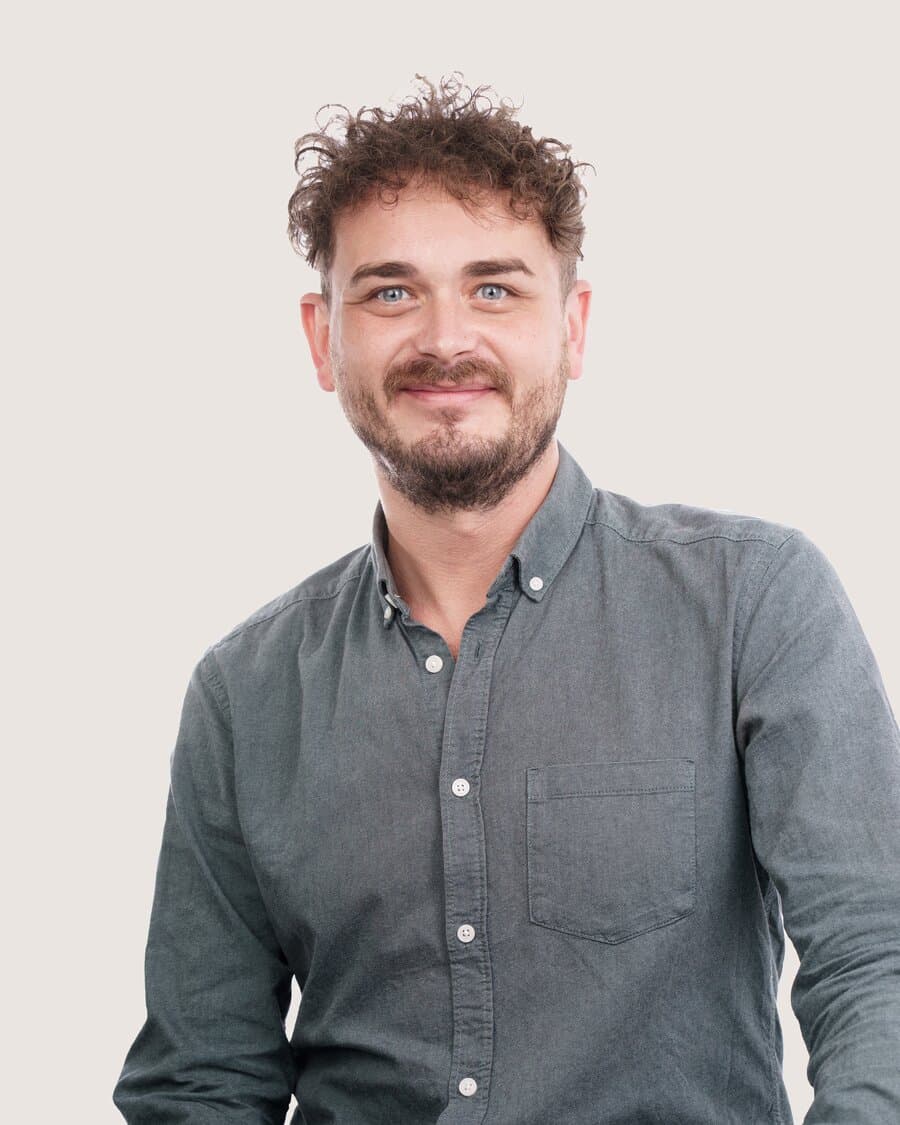 Alex, Talentscout in Berlin, mit lockigem Haar und Bart, lächelt in die Kamera