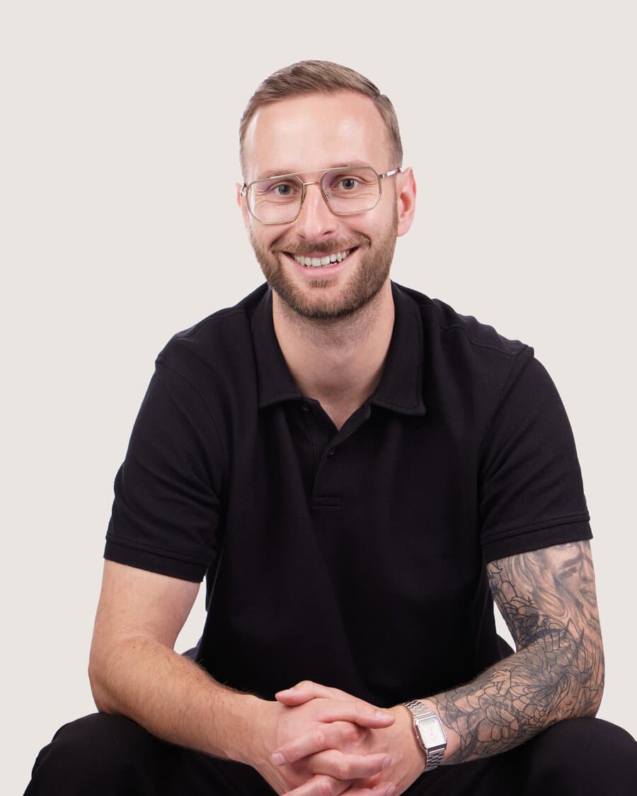 Christopher, Regionalleiter Nord, mit Brille und Bart, im schwarzen Poloshirt, lächelt in die Kamera