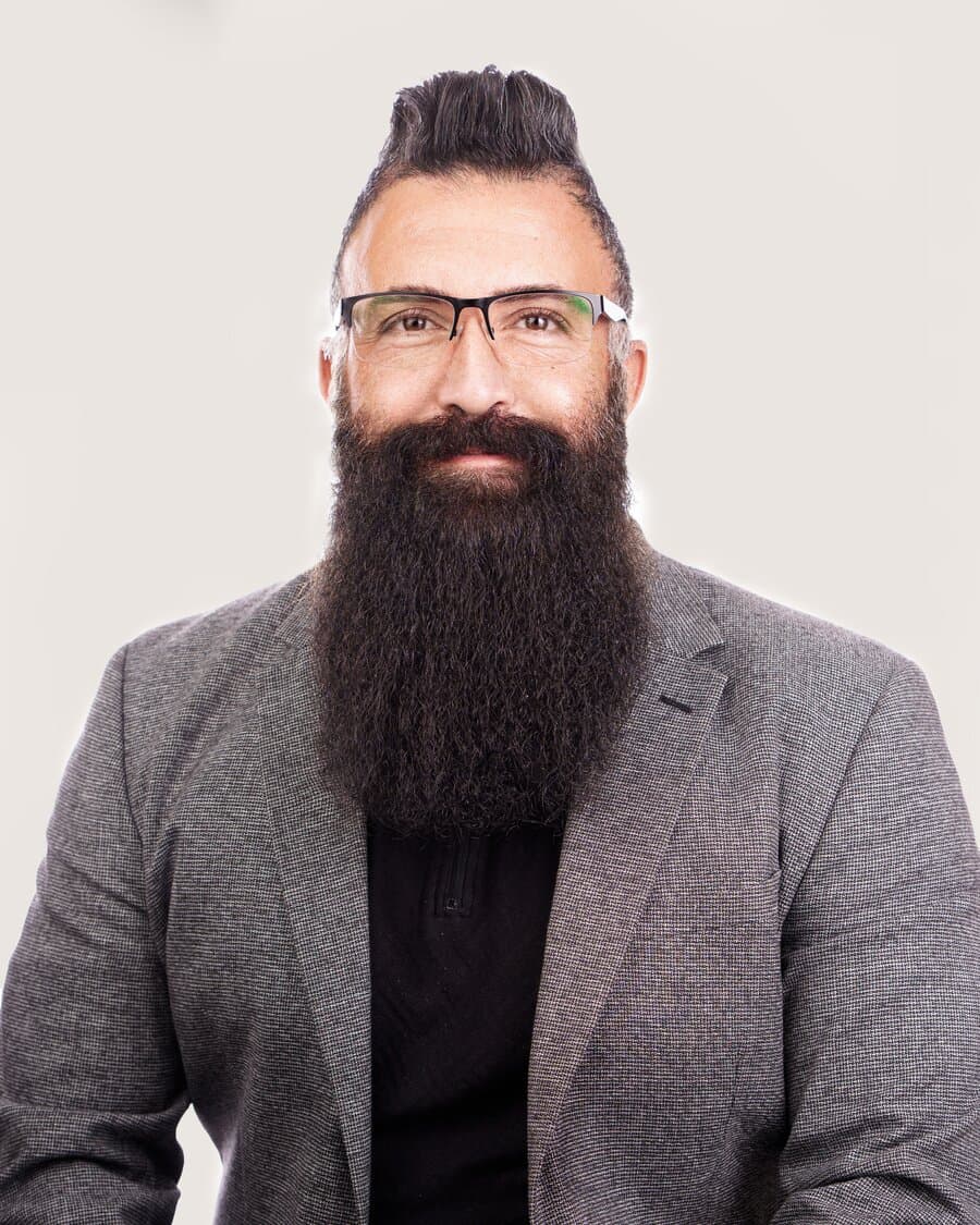 Yasin, Standortleiter in Düsseldorf, mit Brille und langem Vollbart, blickt in die Kamera